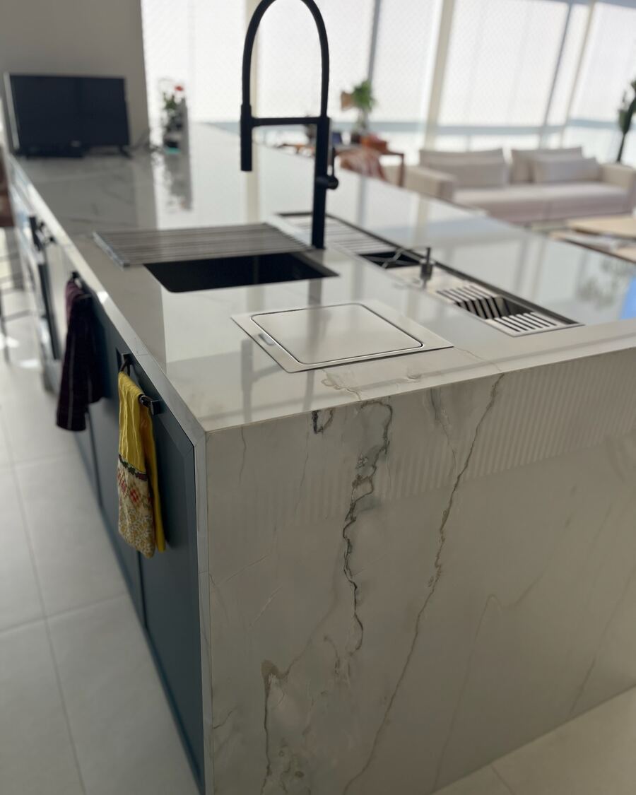 Ilha de cozinha em pedra clara com cuba e torneira integradas